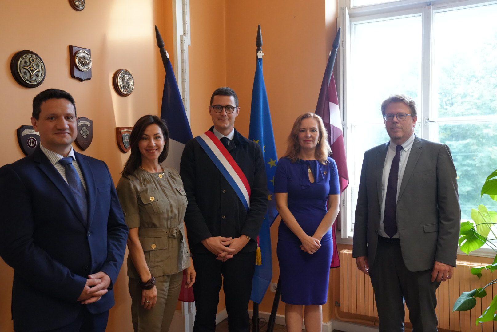 Vincent Caure lors de sa visite à Riga, devant les drapeaux français, européen et letton, aux côtés de partenaires institutionnels et de représentants du Business Club France Latvia.