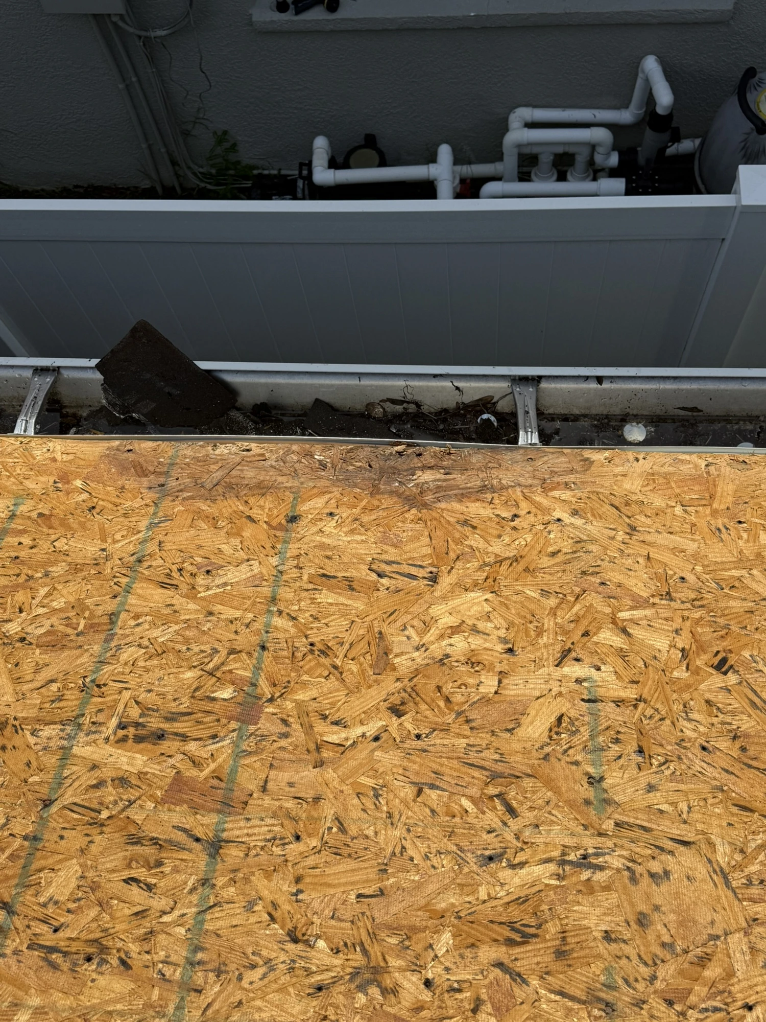 exposed OSB roof decking at the eave with debris in the gutter during a Riverview roof replacement