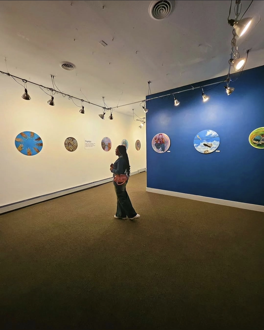 Portrait installation view of visitors looking at Ghetto Visionary artworks