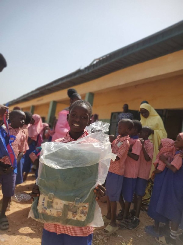 A boy receives his new backpack, still wrapped, at a school outreach