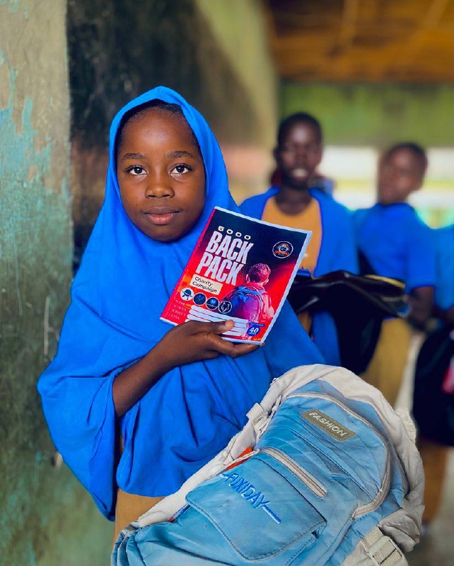 A student holds her new backpack and the campaign flyer