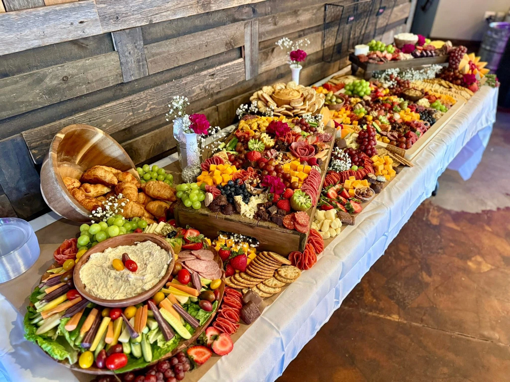 A lavish Owl's Nest grazing table with cured meats, cheeses, fruit, and fresh garnishes